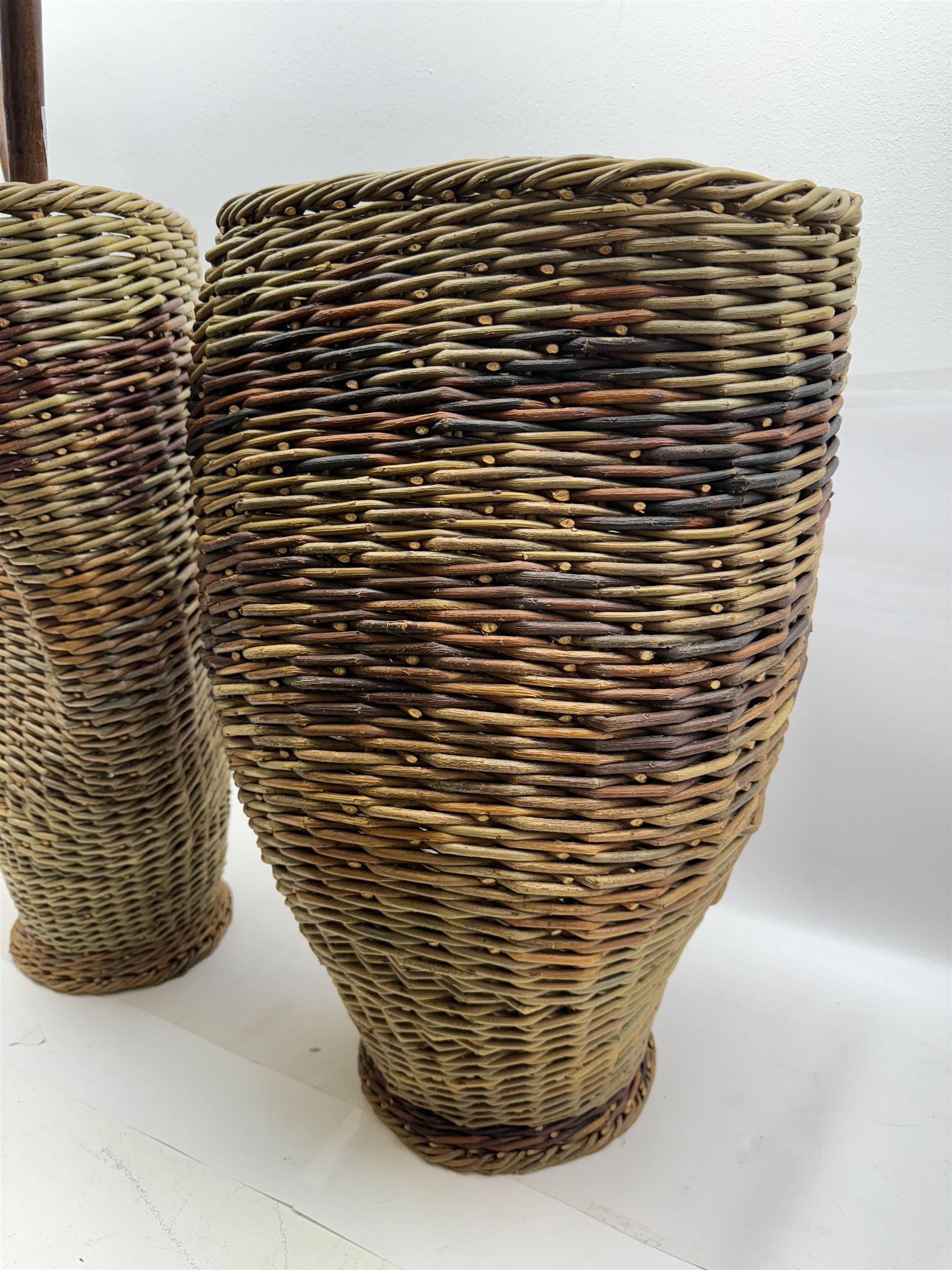 Two rattan baskets, of circular abstract form, together with two crook walking stick, basket H62cm 