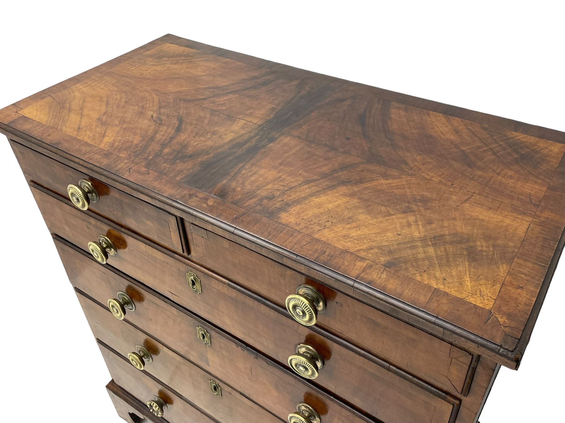 George I walnut chest, moulded rectangular top with book-matched veneers within crossbanding, fitted with two short over four long graduating drawers, moulded drawer fronts with brass handles, on bracket feet, the chest will split into two sections 