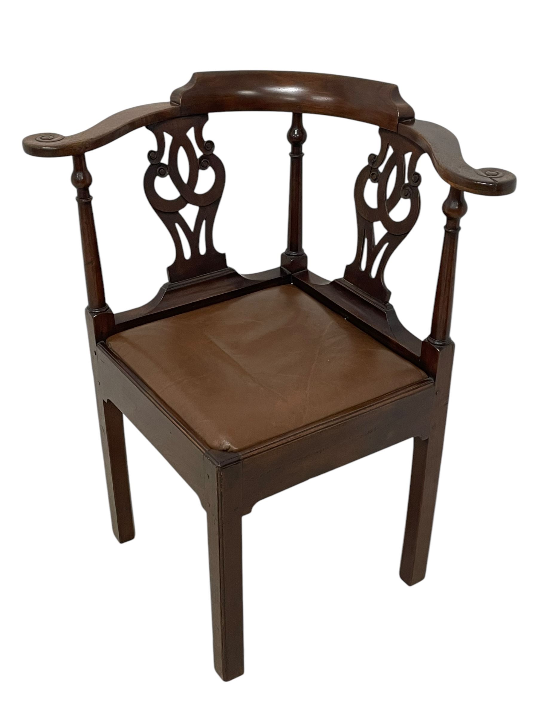 George III mahogany corner elbow chair, curved back rest and shaped arms with scroll carved terminals, on turned supports and pierced scroll carved interlaced splats, drop-in seat upholstered in brown leather, on square supports with inner chamfer and outer moulding 