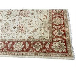 Persian Zeigler beige ground rug, the field decorated with large palmette motifs interconnected with scrolling foliate and branches, enclosed by a wide crimson guard band with repeating stylised plant motifs