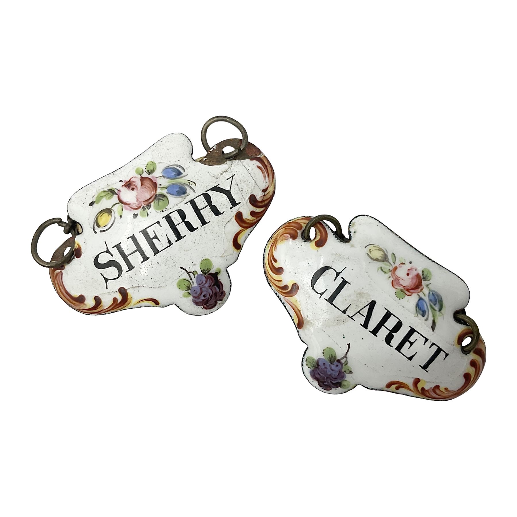 Two late 18th/early 19th century enamel wine labels, each of shaped form, titled 'CLARET', and 'SHERRY' and decorated with floral sprigs and scroll detail upon a white ground, each with suspension chain, each approximately H3.5cm W5cm