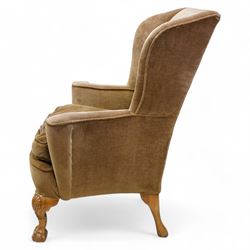 Early 20th century walnut framed wingback armchair, shallow wing back over wide seat with outward rolled arms, curved seat rail, on shell carved ball and claw cabriole feet 