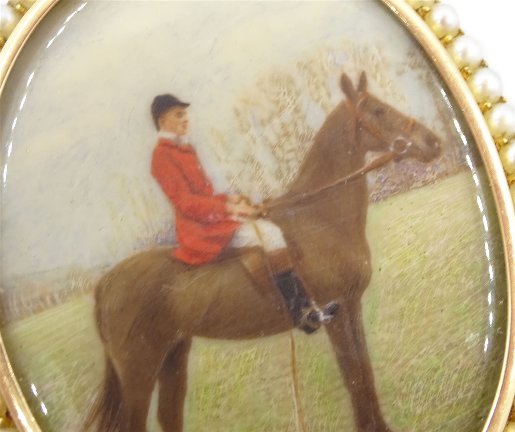 Early 20th century 15ct gold seed pearl locket pendant, with later overpainted print of a huntsman on horseback