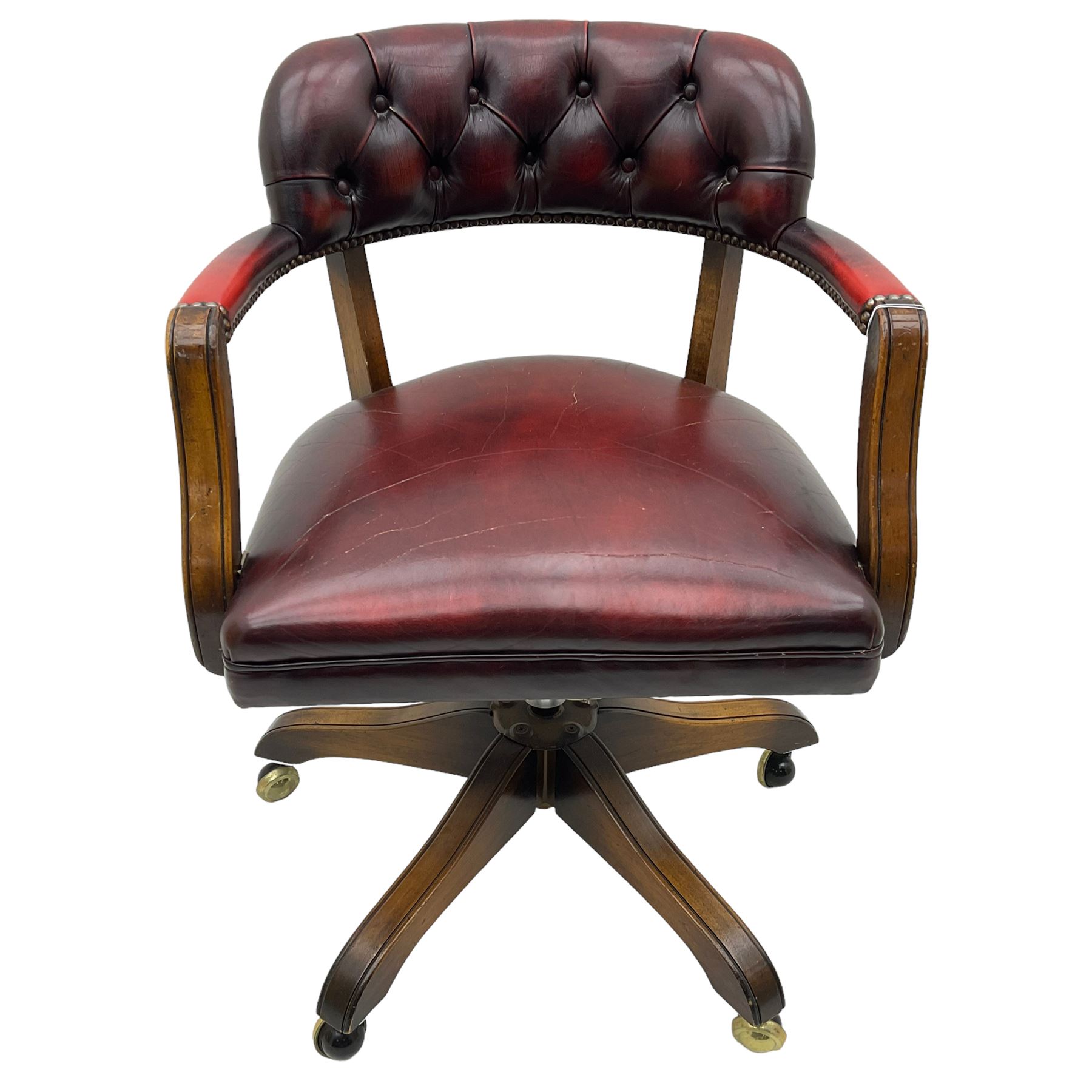 Mid 20th century leather swivel desk chair, oxblood button-tufted upholstery, wooden frame and armrests, on brass castor supports