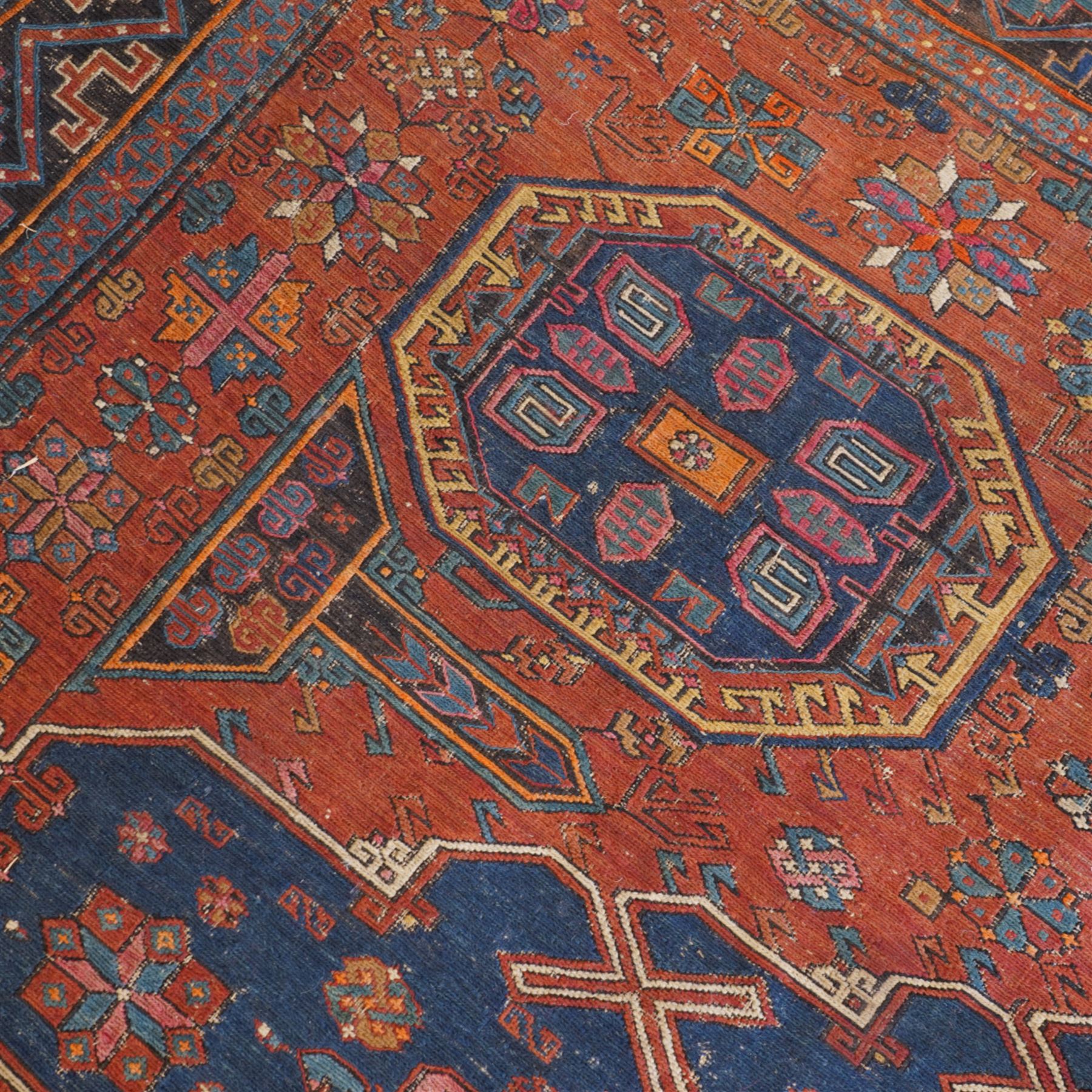 Old Persian red ground flat woven carpet, the field with three large medallions surrounded by small stylised flower head motifs, geometric border enclosed within running water band 346