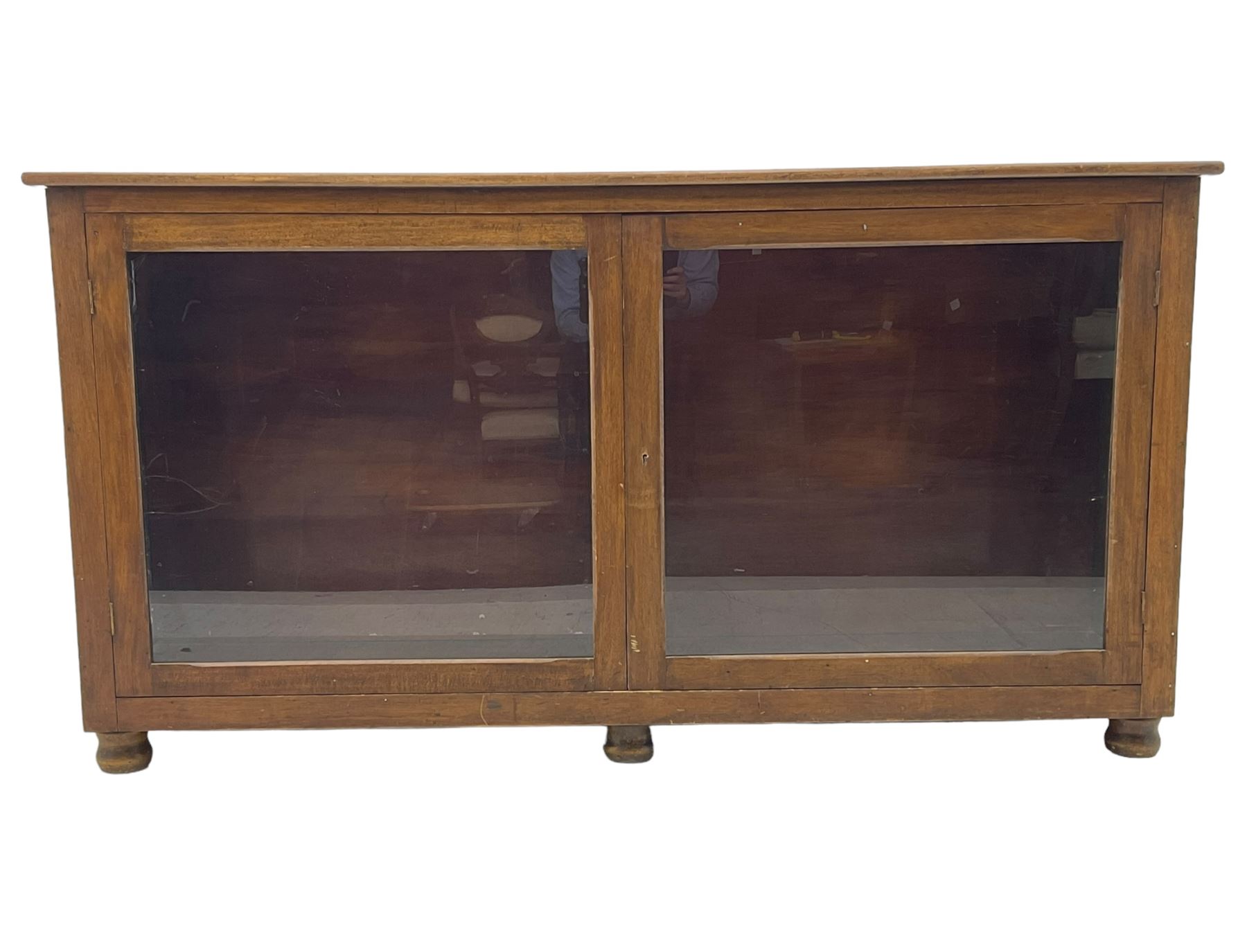 Early 20th century mahogany bookcase, rectangular top over two glazed doors, fitted with four adjustable shelves, on turned bun feet 