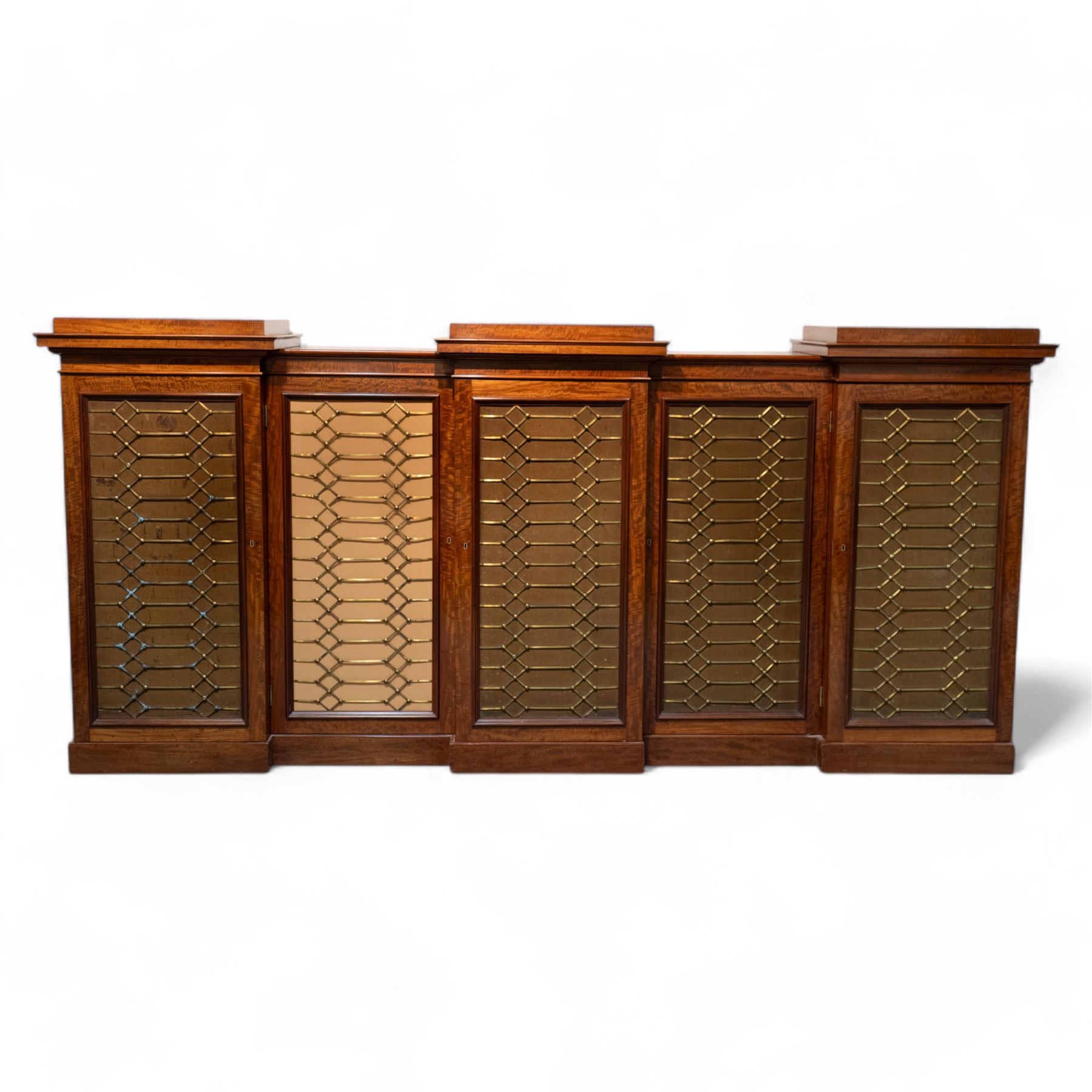 Large 19th century figured mahogany bookcase, enclosed by five brass grille panel doors, the interior fitted with adjustable shelves, double drop centre and break front with raised stepped tops, on plinth base 