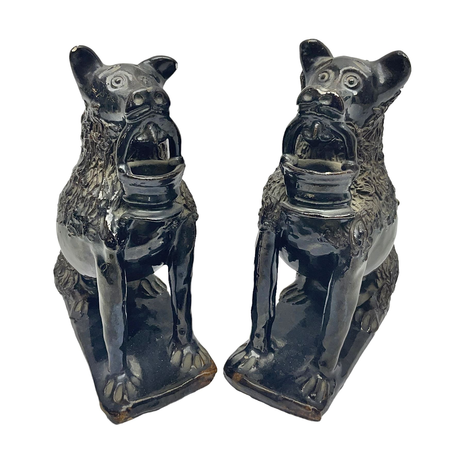 Pair of unusual early English pottery figures, modelled in the form of seated dogs with baskets between their jaws, the tails forming whistles, each upon rectangular base, overall H22cm