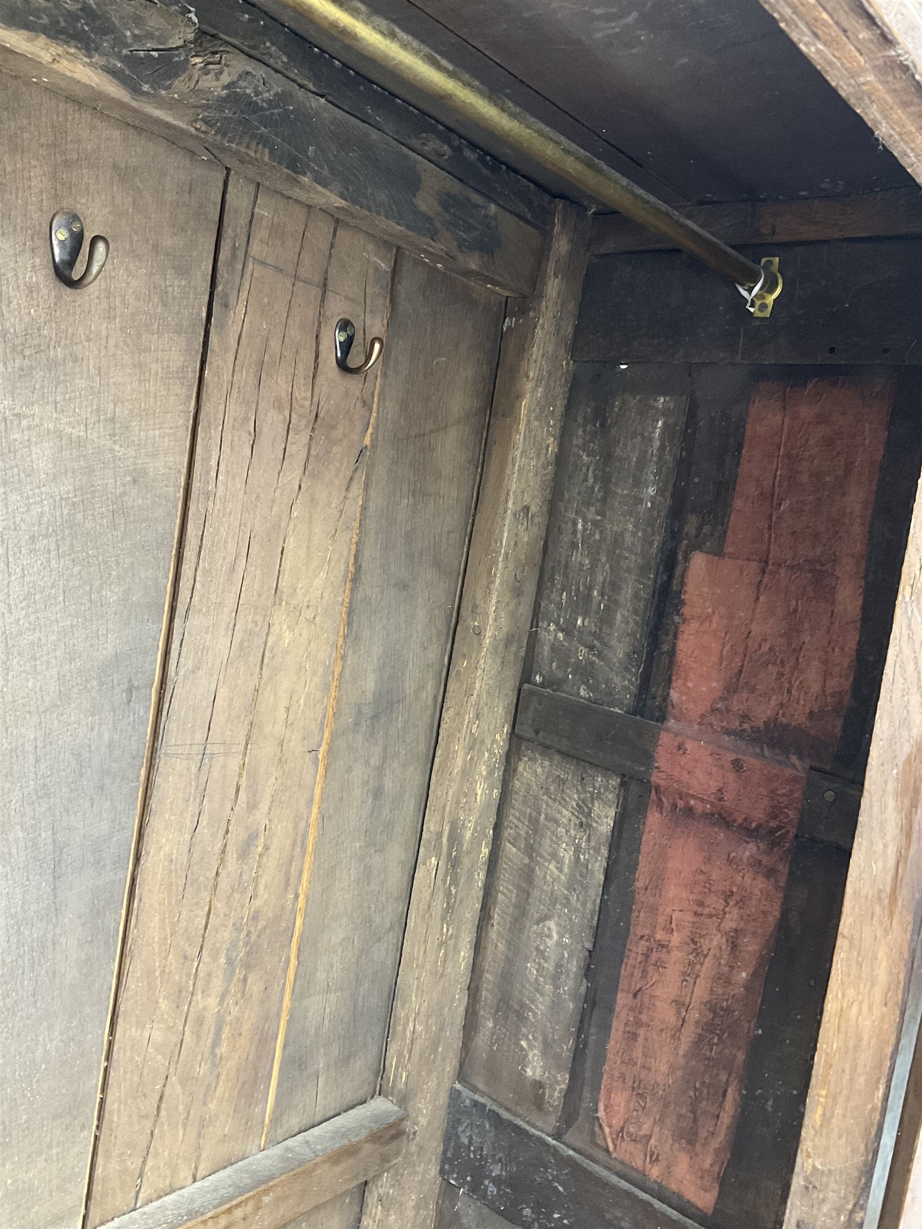 17th century and later oak hall cupboard, panelled front and sides with moulded frame, enclosed by single door with wrought metal hinges and handle, the interior fitted with hooks, on stile supports 