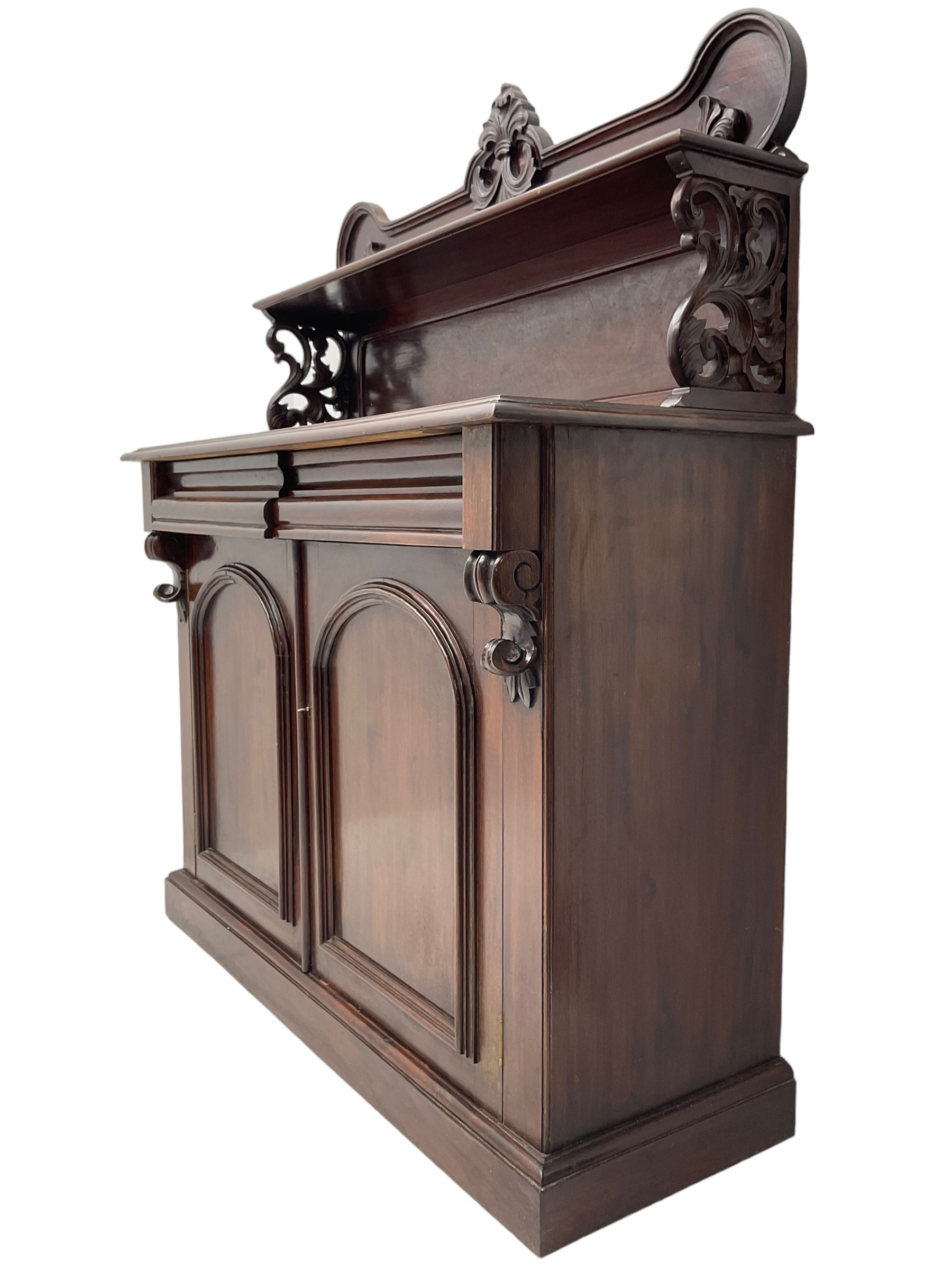 Victorian mahogany chiffonier, raised shaped back with foliage scroll carved mounts, on fretwork and carved bracket supports, moulded rectangular top over two frieze drawers and double panelled cupboard, on moulded plinth base