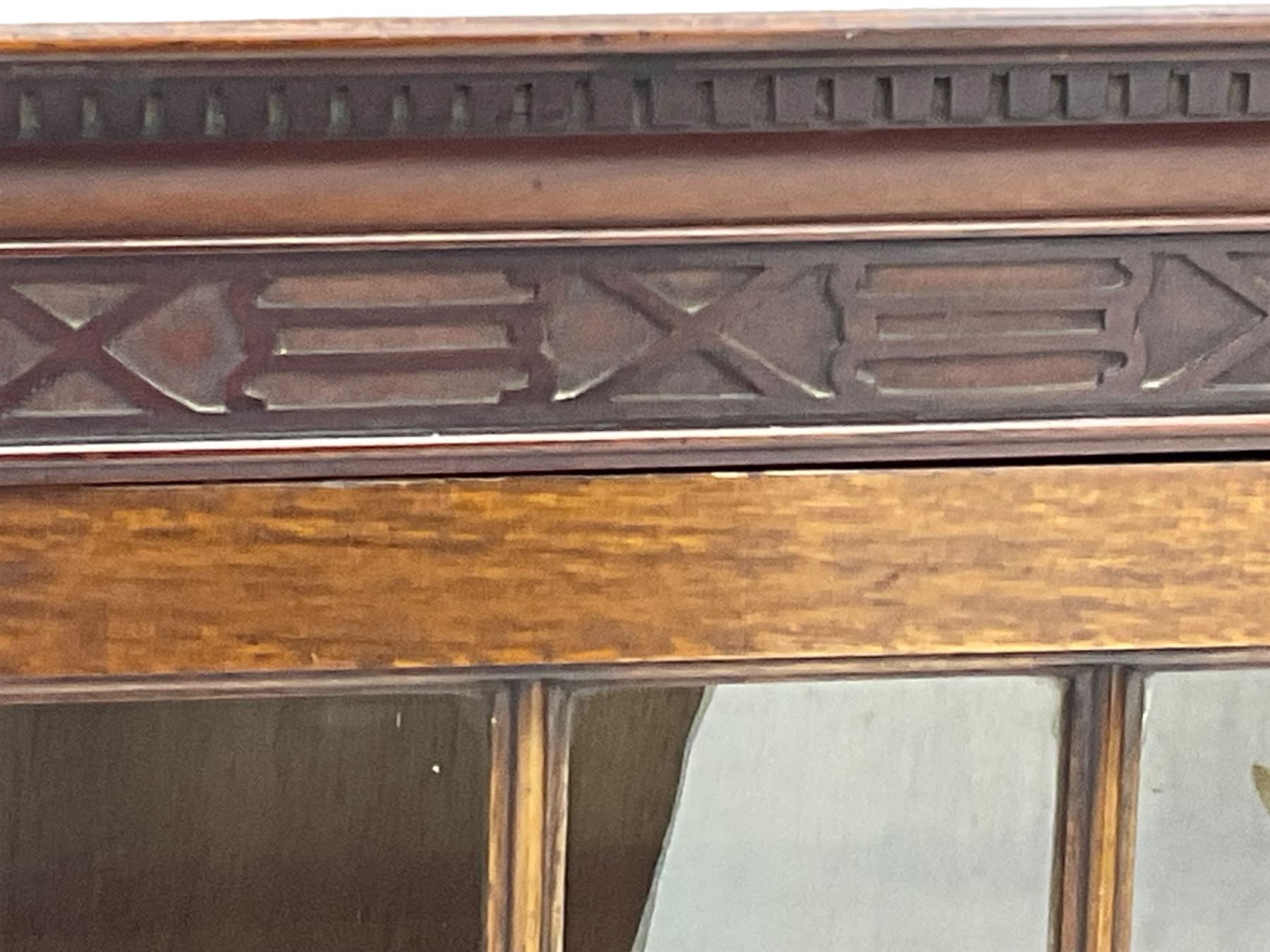 Early 20th century mahogany bookcase, projecting dentil cornice over blind fretwork frieze, enclosed by two astragal glazed doors, on shaped bracket feet 