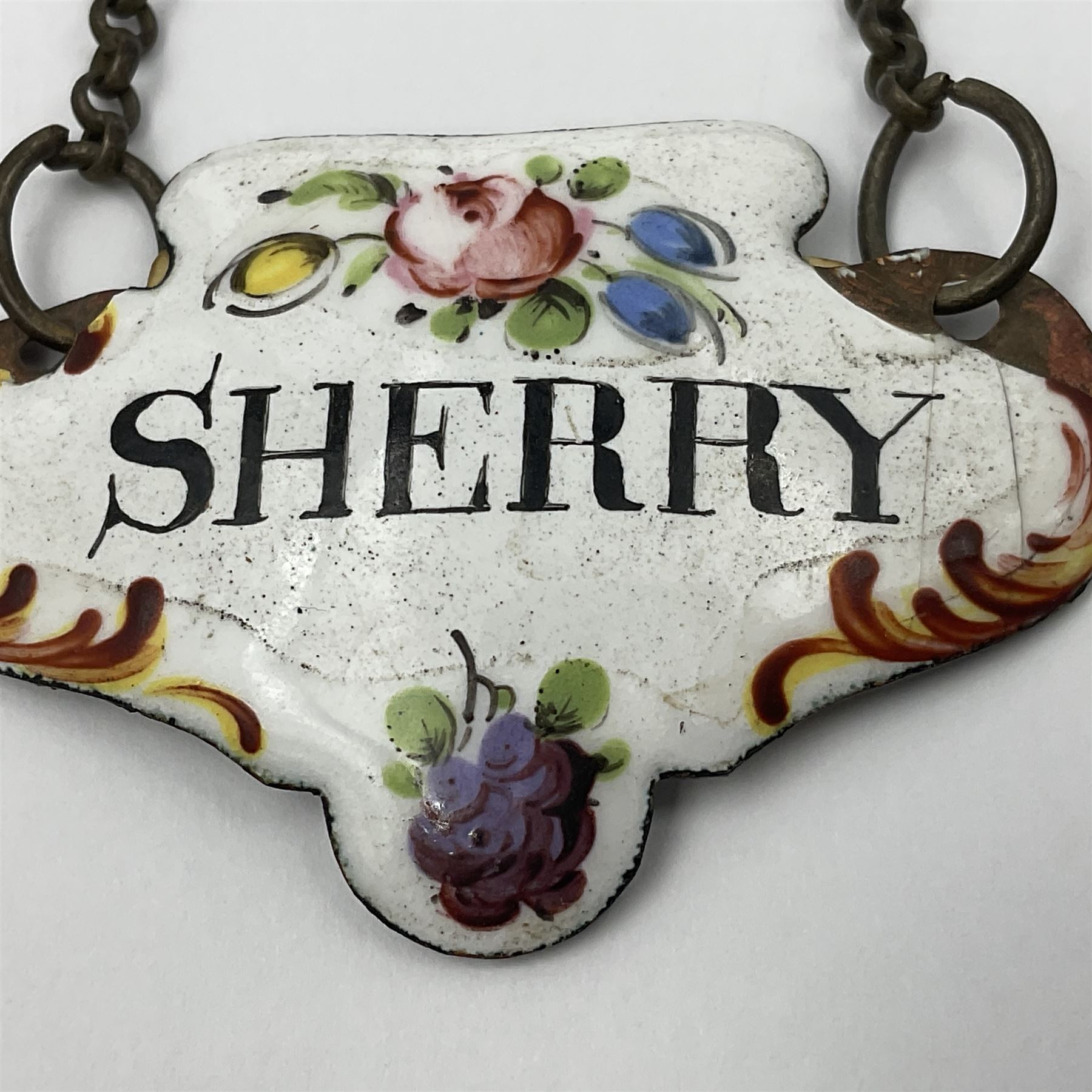 Two late 18th/early 19th century enamel wine labels, each of shaped form, titled 'CLARET', and 'SHERRY' and decorated with floral sprigs and scroll detail upon a white ground, each with suspension chain, each approximately H3.5cm W5cm