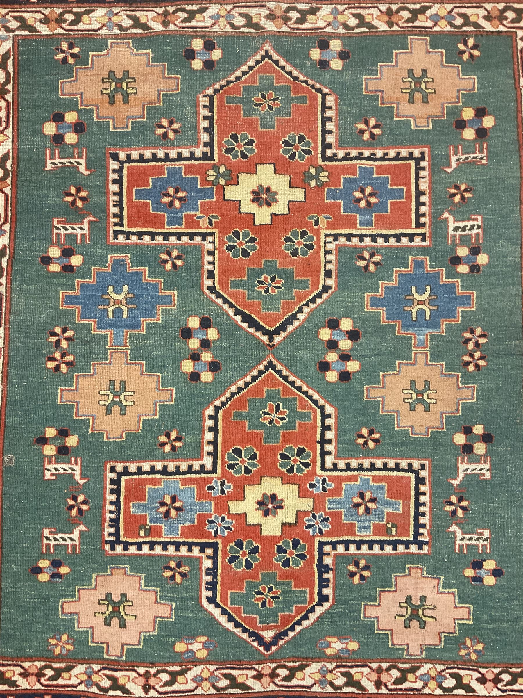 Caucasian turquoise ground rug, two medallions on a field decorated with stylised animal and geometric motifs, the guarded border decorated with further geometric motifs