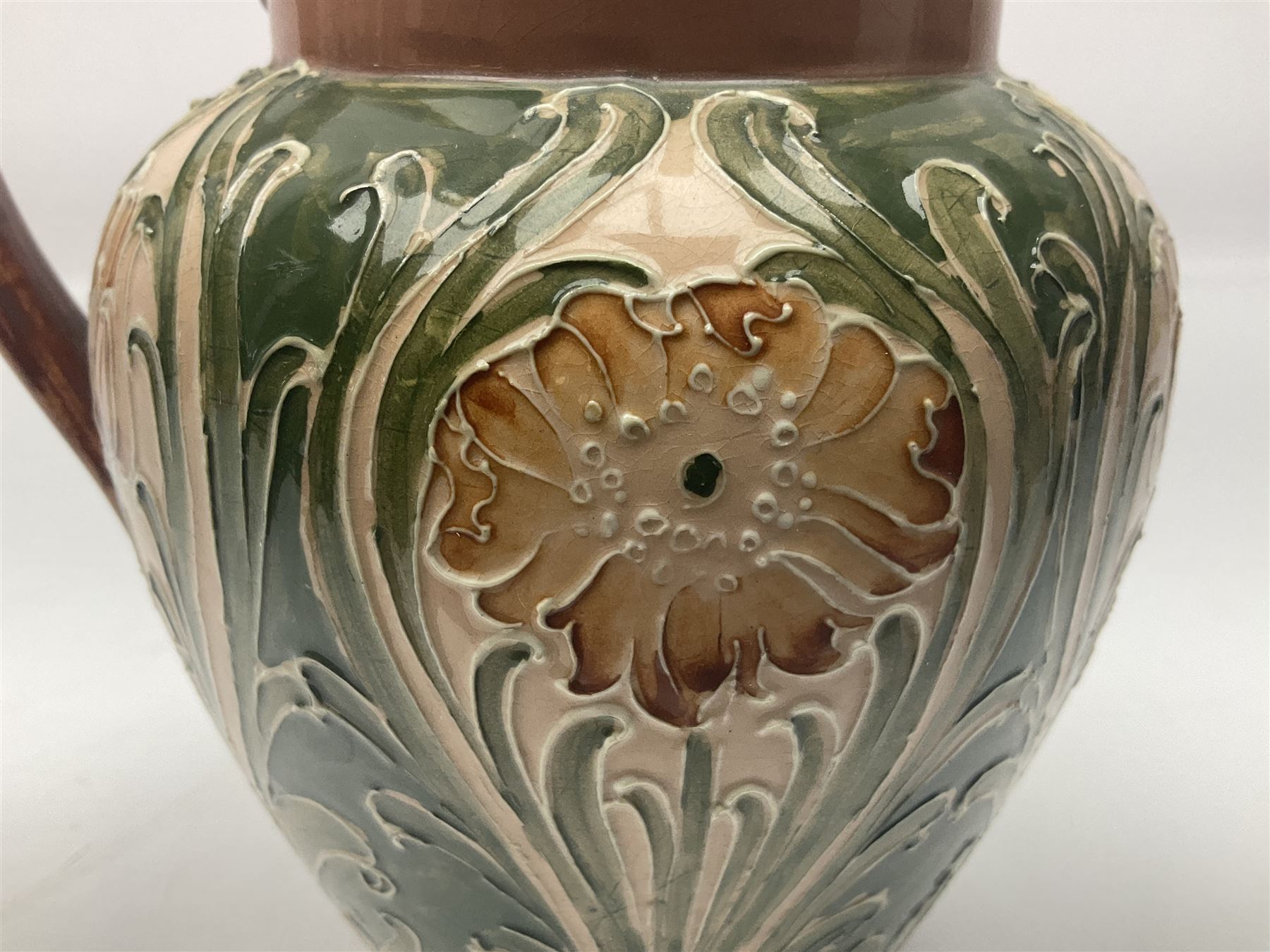 Moorcroft Macintyre Burslem jug, circa 1902, decorated with a motif of stylised flowers amongst scrolling foliage, in shades of brown and green on a peach ground, with printed mark beneath, H16cm