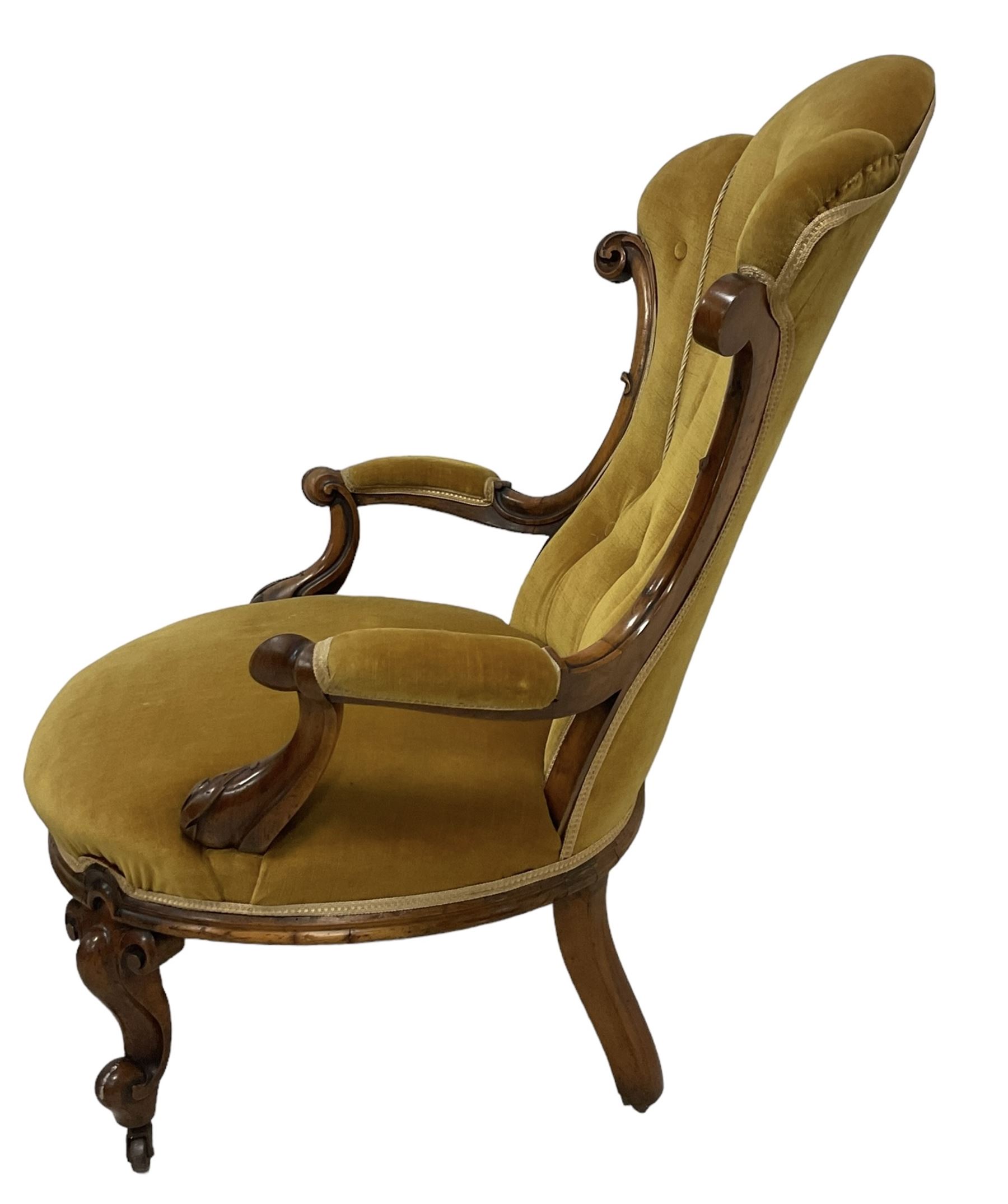 19th century walnut framed open armchair, scallop shaped back with c-scroll uprights, upholstered in yellow buttoned velvet fabric with sprung seat, arm terminals carved with acanthus leaves, raised on scrolling cabriole supports with castors