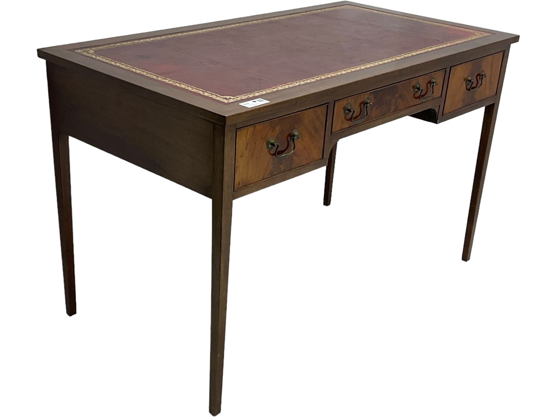 Mid-to-late 20th century mahogany writing desk, the rectangular top with a tooled red leather insert bordered with gilt detailing, three cock-beaded drawers with brass handles, the narrow central drawer flanked by two wider drawers, standing on square tapered legs