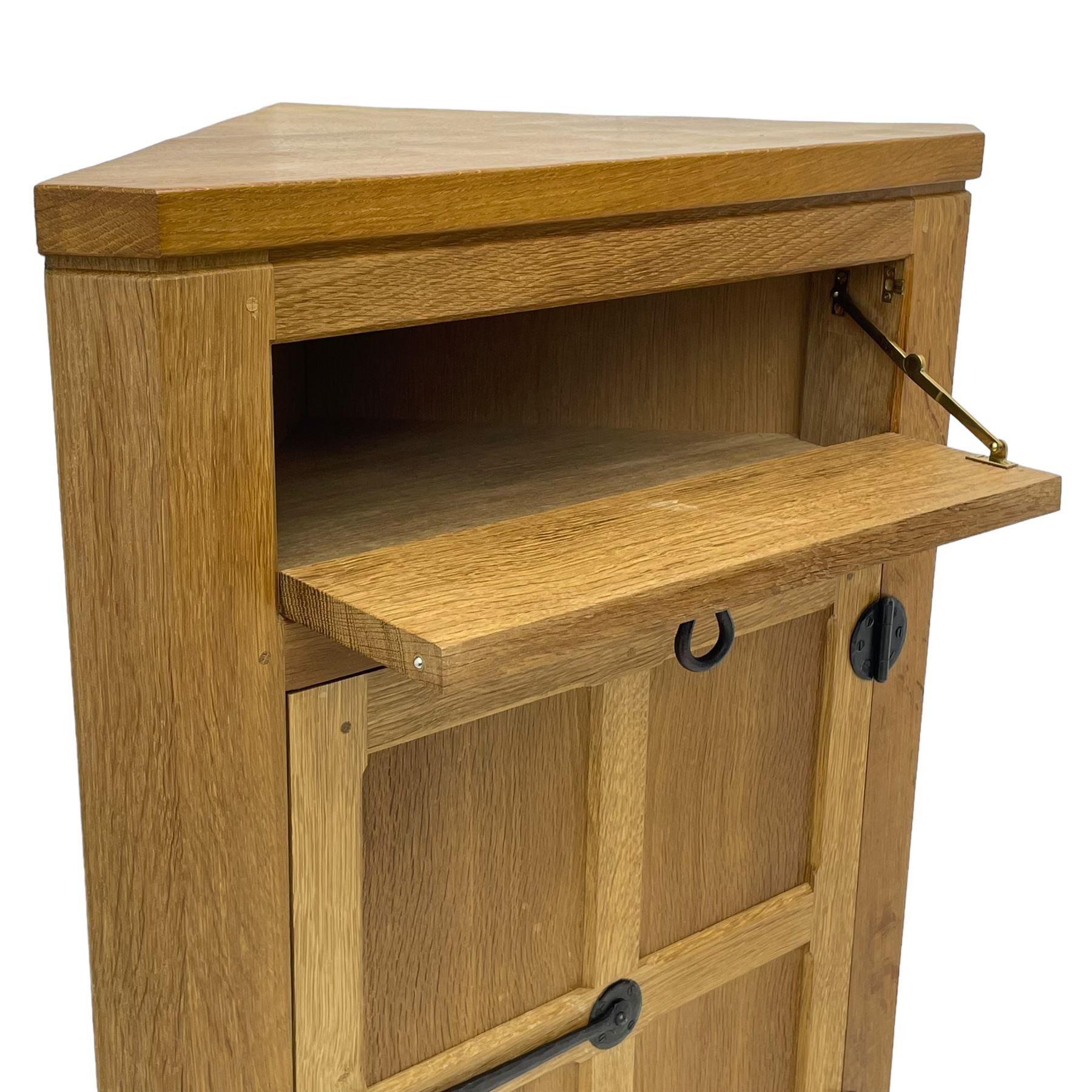 Mouseman - oak floor standing corner cupboard, fall front compartment over single panelled door, with wrought metal loop handle and latch, on moulded plinth base, carved in relief with mouse signature, by the workshop of Robert Thompson, Kilburn 