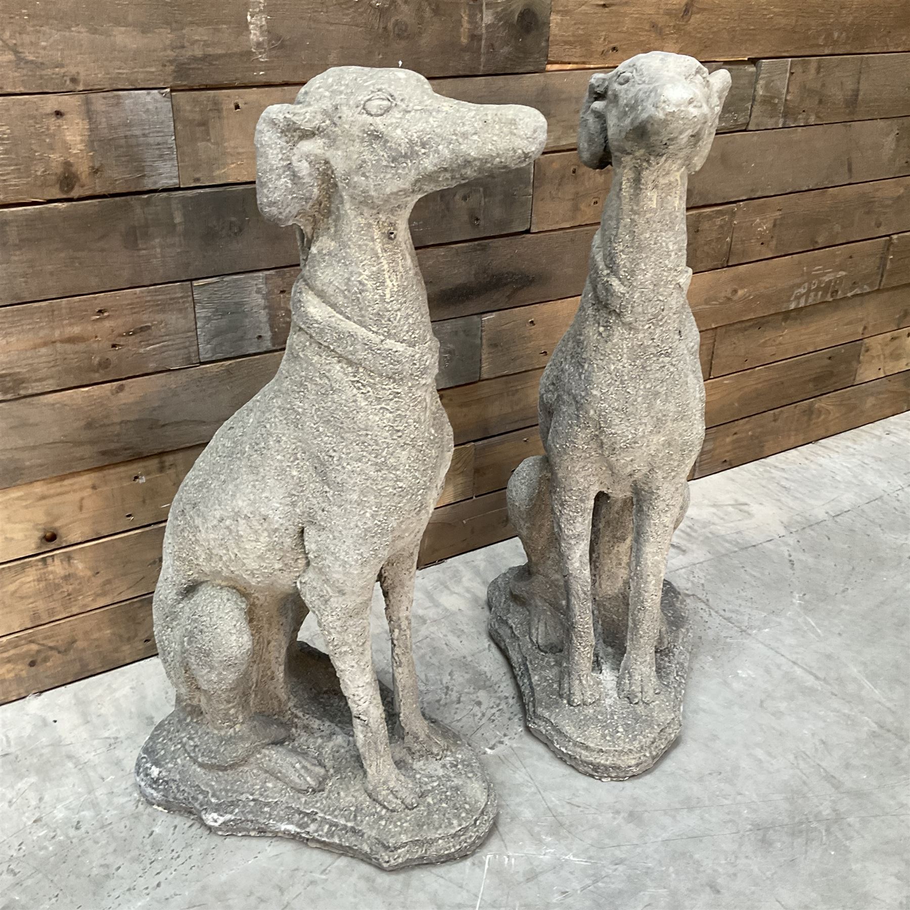 Pair of cast stone French lurchers, seated pose, on shaped plinth