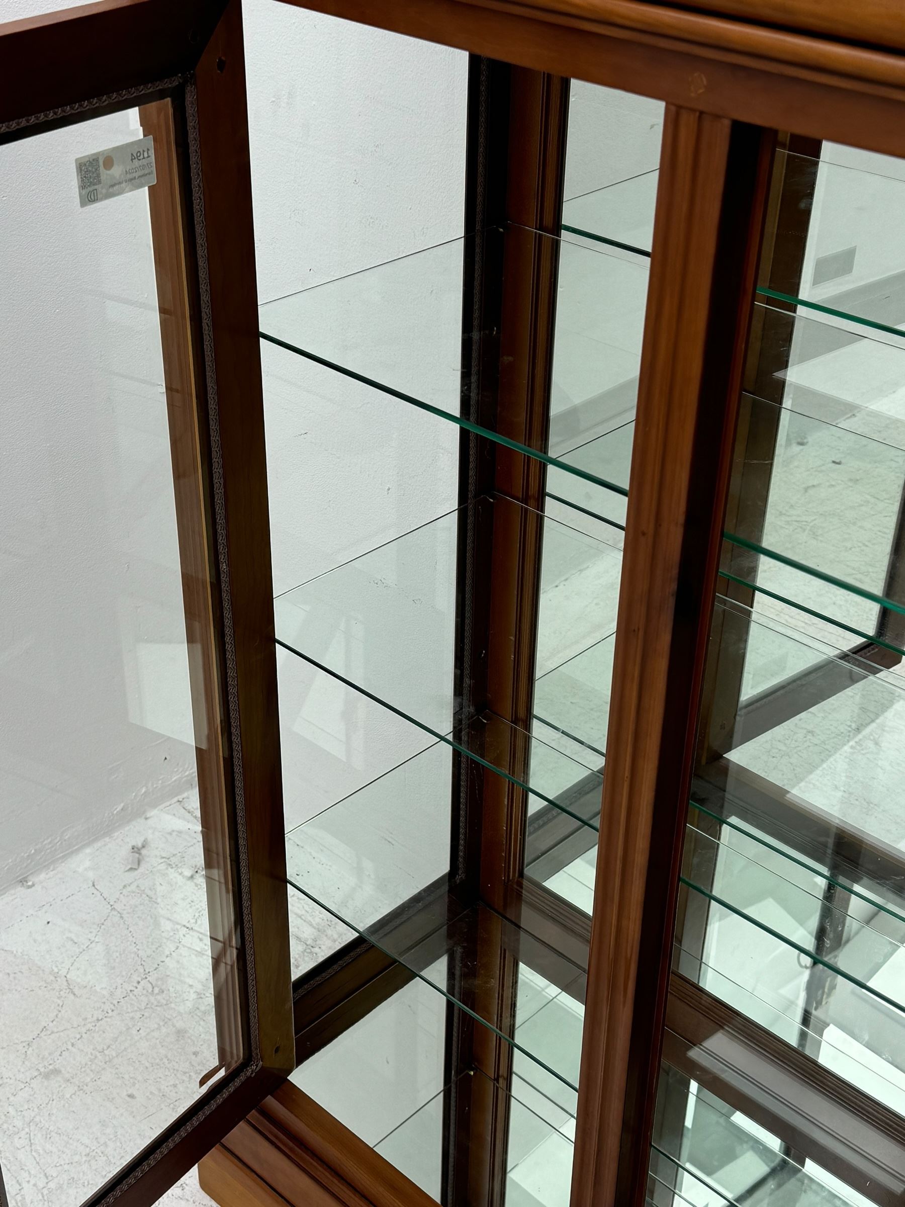 20th century cherry wood display cabinet, projecting cornice over two glazed doors with bevelled panes flanked by fluted support columns, enclosing three adjustable glass shelves with mirror-back surface, supported by shaped bracket feet