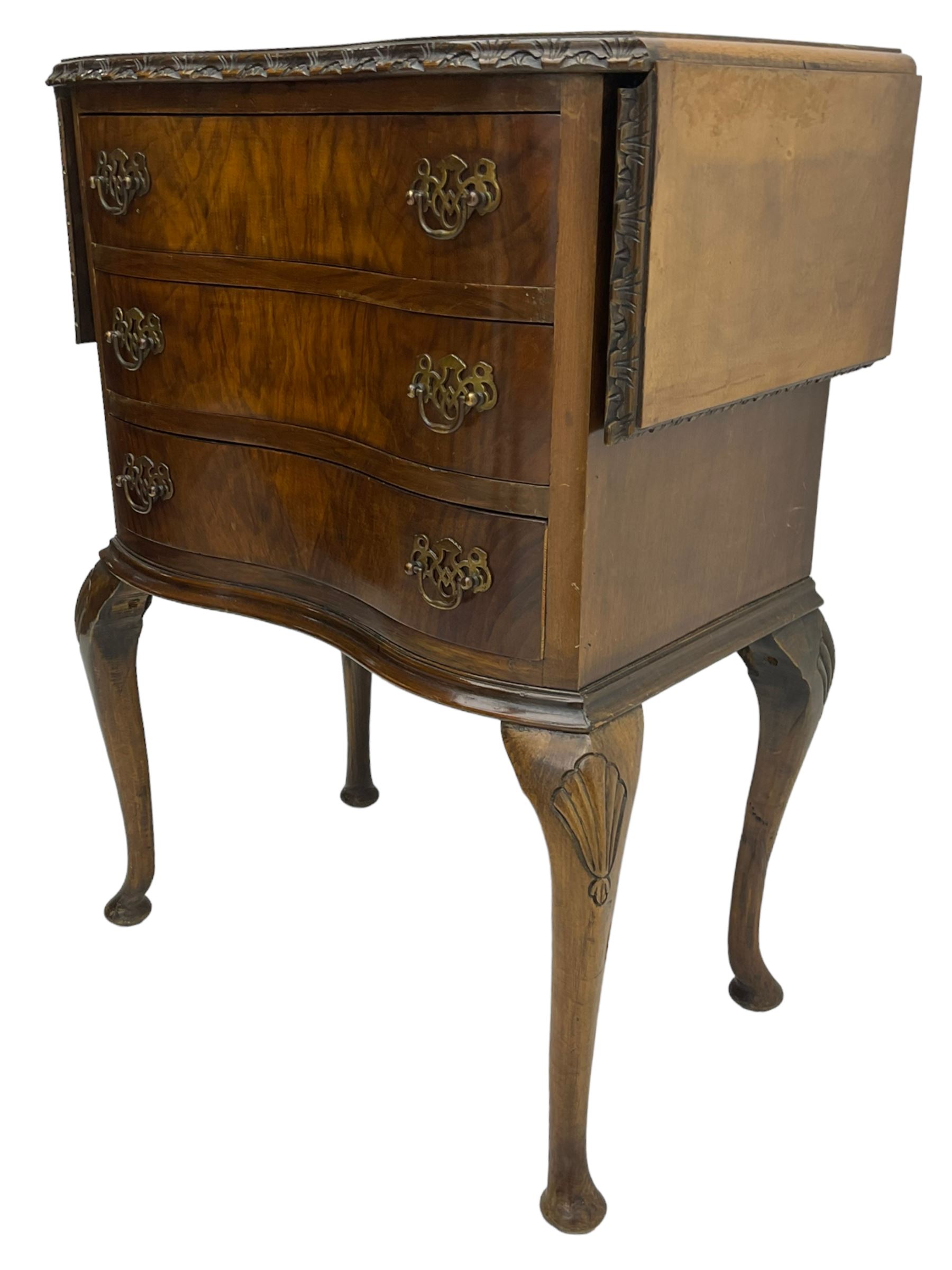 Early to mid-20th century figured walnut lamp table, shaped drop-leaf top with foliate carved edge, fitted with three drawers, on shell carved cabriole supports