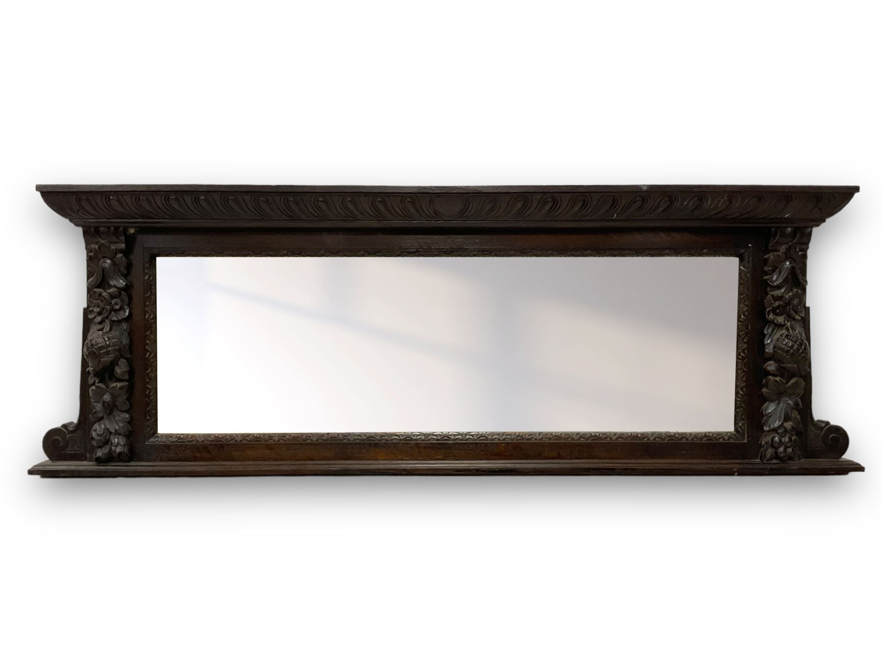 Victorian heavily carved oak wall mirror, projecting gadroon carved ovolo cornice, bevelled mirror plate within a lunette carved frame, decorated with applied fruit and foliage carved mounts, scroll carved brackets 