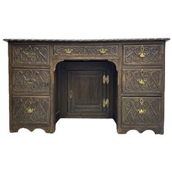 Victorian carved oak kneehole desk, the rectangular top with carved edge, above central drawer with carved front and brass handles, central kneehole with cupboard door, flanked by two banks of three graduating drawers each with similarly carved decoration, on shaped plinth base with castors