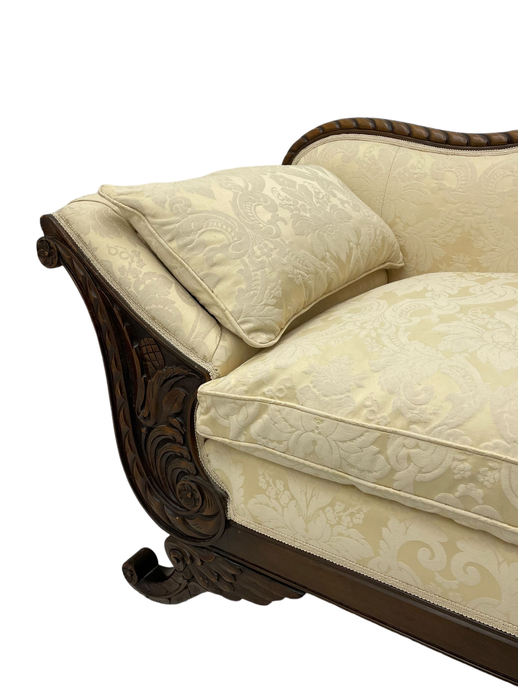 Victorian design walnut framed settee, shaped camelback with gadroon carved edge and central feather motif, upholstered in cream damask fabric with scrolling floral pattern, S-scroll arm facias carved with flower head and curled leaves, feather carved C-scroll splayed feet 