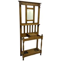 Early 20th century oak hall stand, bevelled mirror back over hinged compartment, on turned front supports 