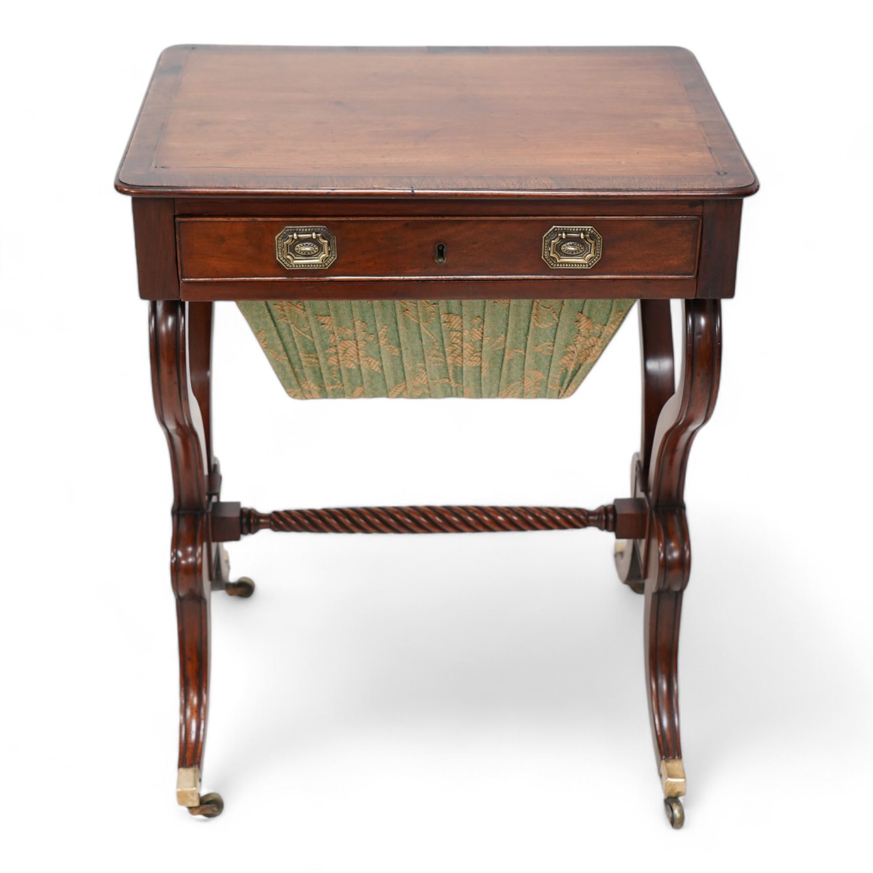 Regency mahogany work table, rectangular top with banded and moulded edge inlaid with checkered stringing, fitted with single cock-beaded drawer over upholstered sliding well, raised on scrolled twin end supports, united by a spiral-turned stretcher, on splayed supports with brass cups and castors