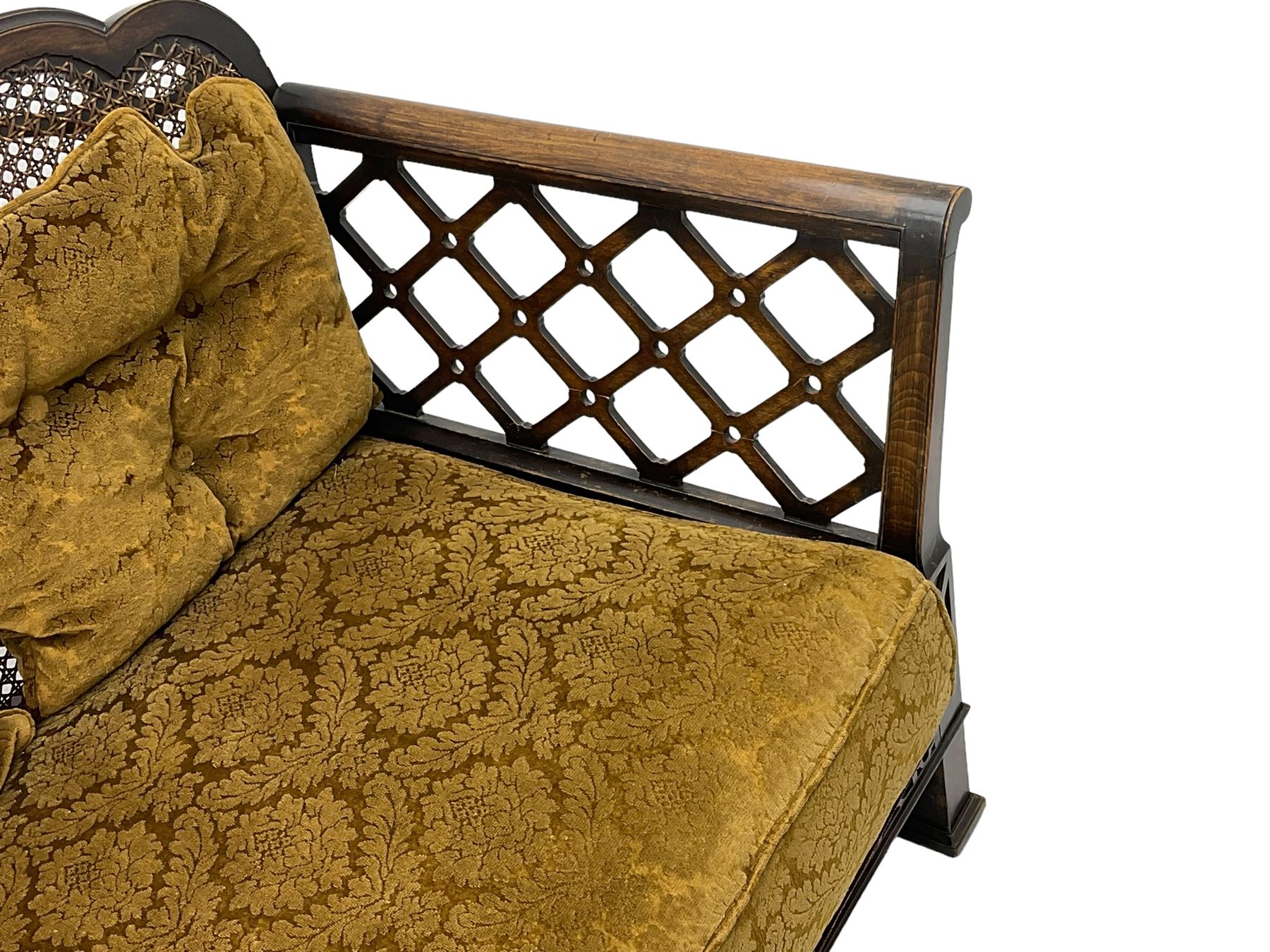 Early 20th century three-piece bergère suite - three seat sofa (W177cm, H82cm, D75cm); pair of matching armchairs (W84cm); single caned back with 'cock-pen' panelled arms, upholstered in foliate pattern fabric, blind fretwork lower frieze over square feet 