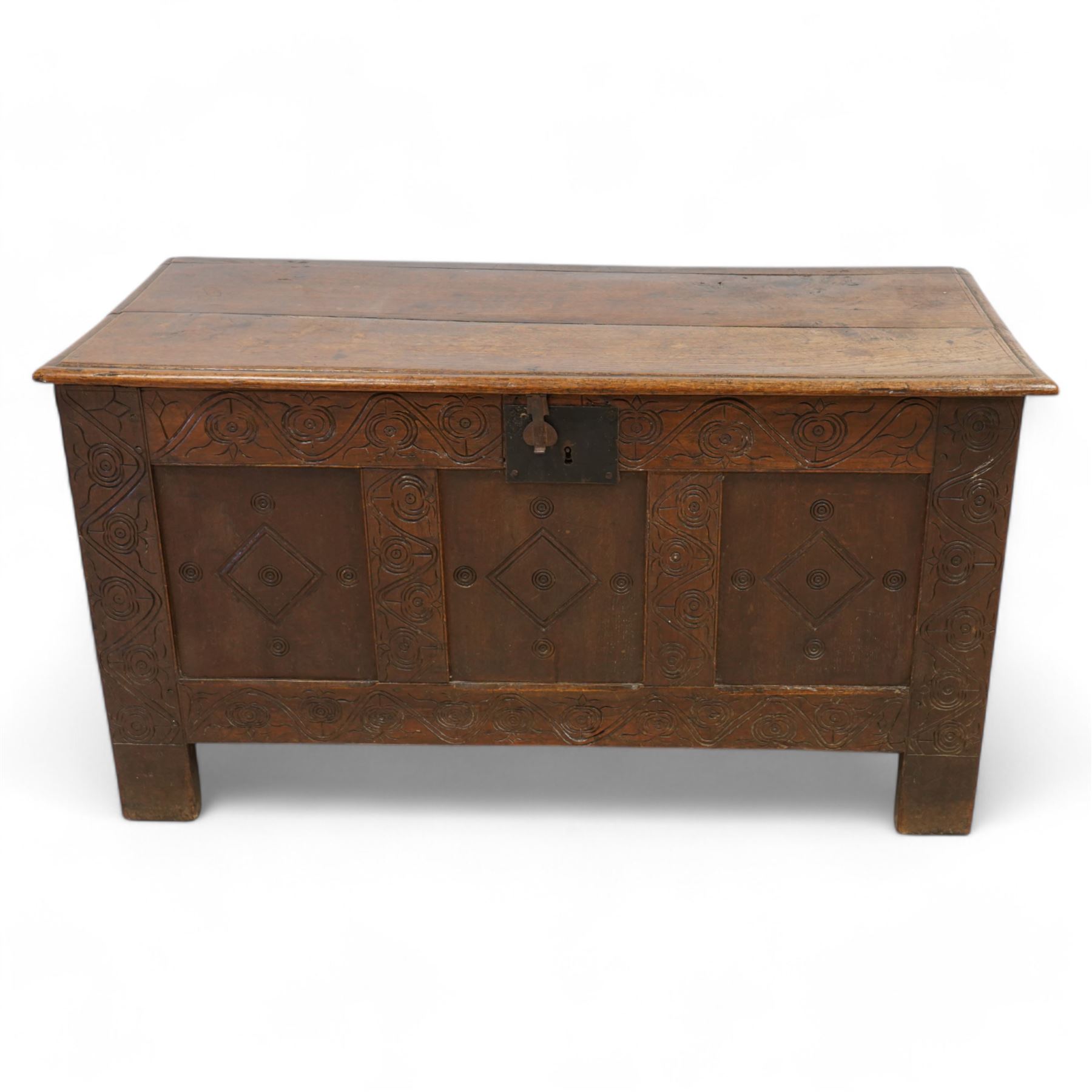 18th century oak blanket box, moulded rectangular hinged lid over three panel front, carved with stylised plant motifs and lozenges, on stile supports 