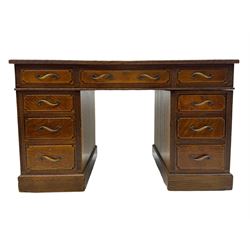 20th century oak twin pedestal desk, rectangular top with inset leather writing surface, fitted with nine drawers with chamfered edges to the raised panels, each with curved brass handles with scroll ends and keyholes, fluted detailing to the top and between the drawers, on moulded plinth base with castors