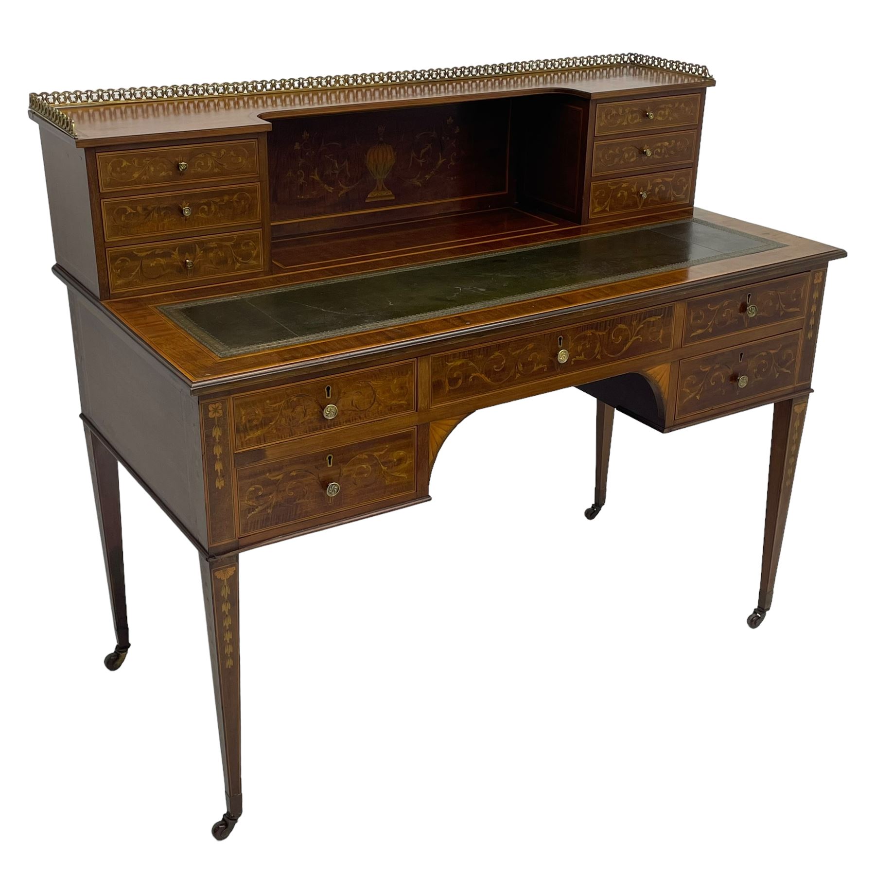 Edwardian inlaid mahogany writing desk, raised galleried back over inlaid central urn with scrolling leafy branches and six small drawers, satinwood banded rectangular moulded top with tooled leather inset, fitted with five drawers, the drawer facias inlaid with scrolling foliage and satinwood banding, square tapering supports inlaid with trailing bell flowers, on brass and ceramic castors 