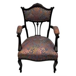 Late Victorian mahogany framed armchair, upholstered in muted purple fabric with iridescent floral pattern and nailhead trim, central foliate carved splat over padded scrolled arms, on cabriole supports fitted with castors