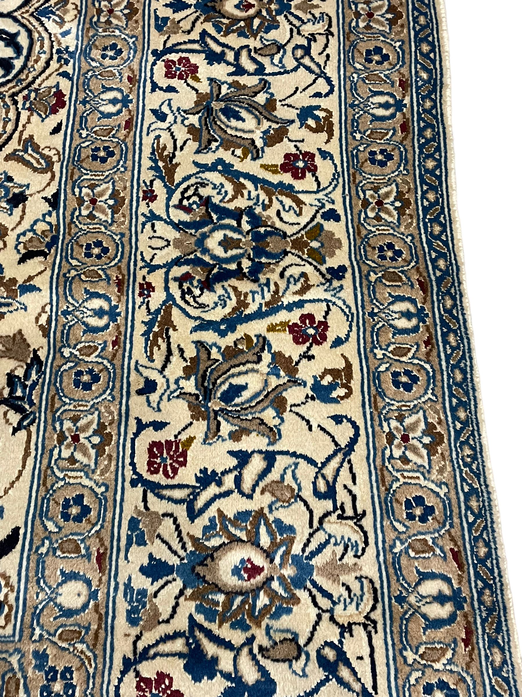 Persian ivory ground carpet, overall floral pattern with central rosette medallion, the field decorated with interlaced leafy branches and stylised plant motifs, guarded repeating border with repeating design