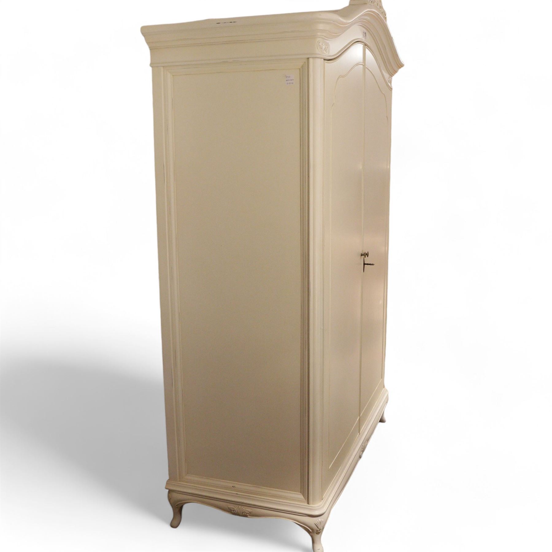 French design cream painted Armoire, foliate scroll decorated pediment over two doors, fitted with hanging rails and shelves, on cabriole feet