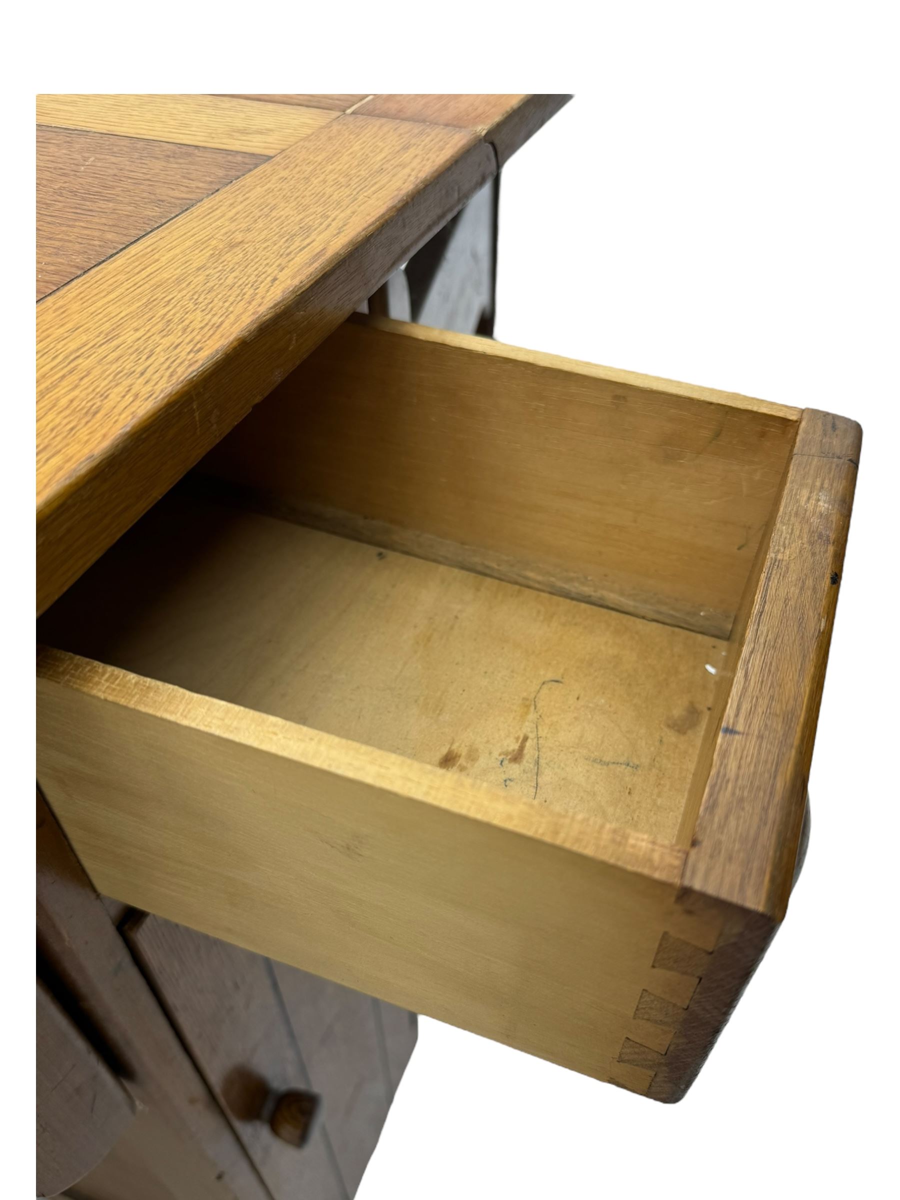 Early 20th century oak drop-leaf table, in the style of Harris Lebus, featuring rectangular top over central pedestal base, with two drawers and two cupboards, on gateleg supports