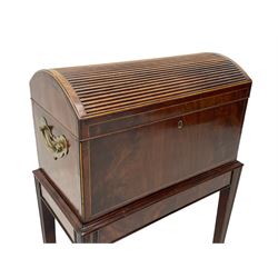 George III figured mahogany cellarette, hinged dome top with false tambour reeded panel enclosing eight bottle divisions, figured front over moulded upper edge, boxwood stringing throughout, on square tapering moulded supports, fitted with brass carrying handles 