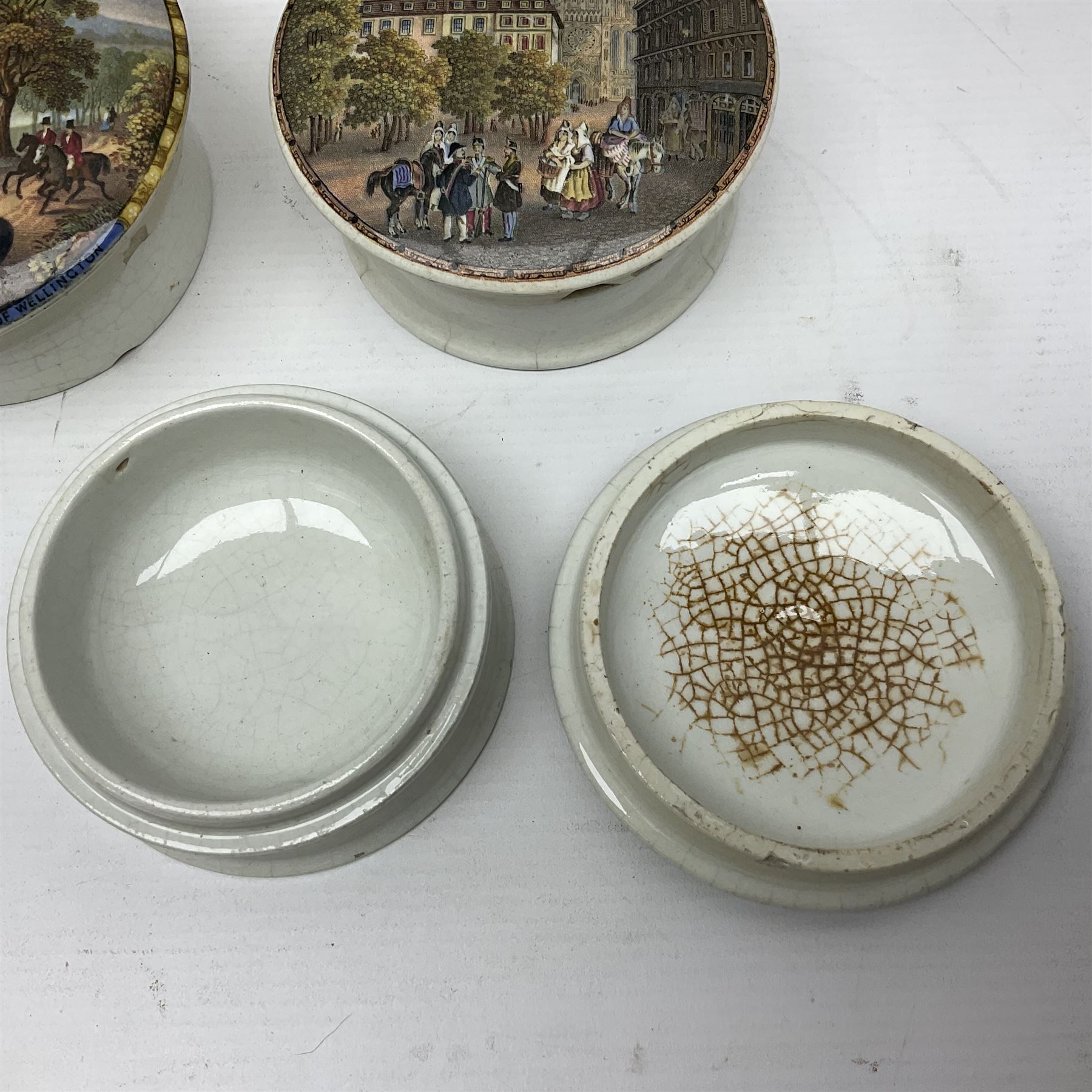 Seven 19th century Prattware pot lids with associated bases, including 'The Snow Drift', 'Strathfieldsaye The Seat of the Duke of Wellington', 'The Late Prince Consort', 'French Street Scene', Lend a Bite', 'Dr Johnson' and 'Sandringham the Seat of HRH The Prince of Wales', largest D12cm (7)