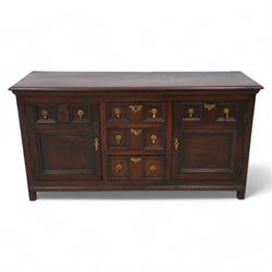 George III elm dresser base, the rectangular top with moulded edge, fitted with three central graduating twin-panelled drawers, flanked by two cupboard doors moulded with false drawer facias over large panels, lower moulded edge over stile feet