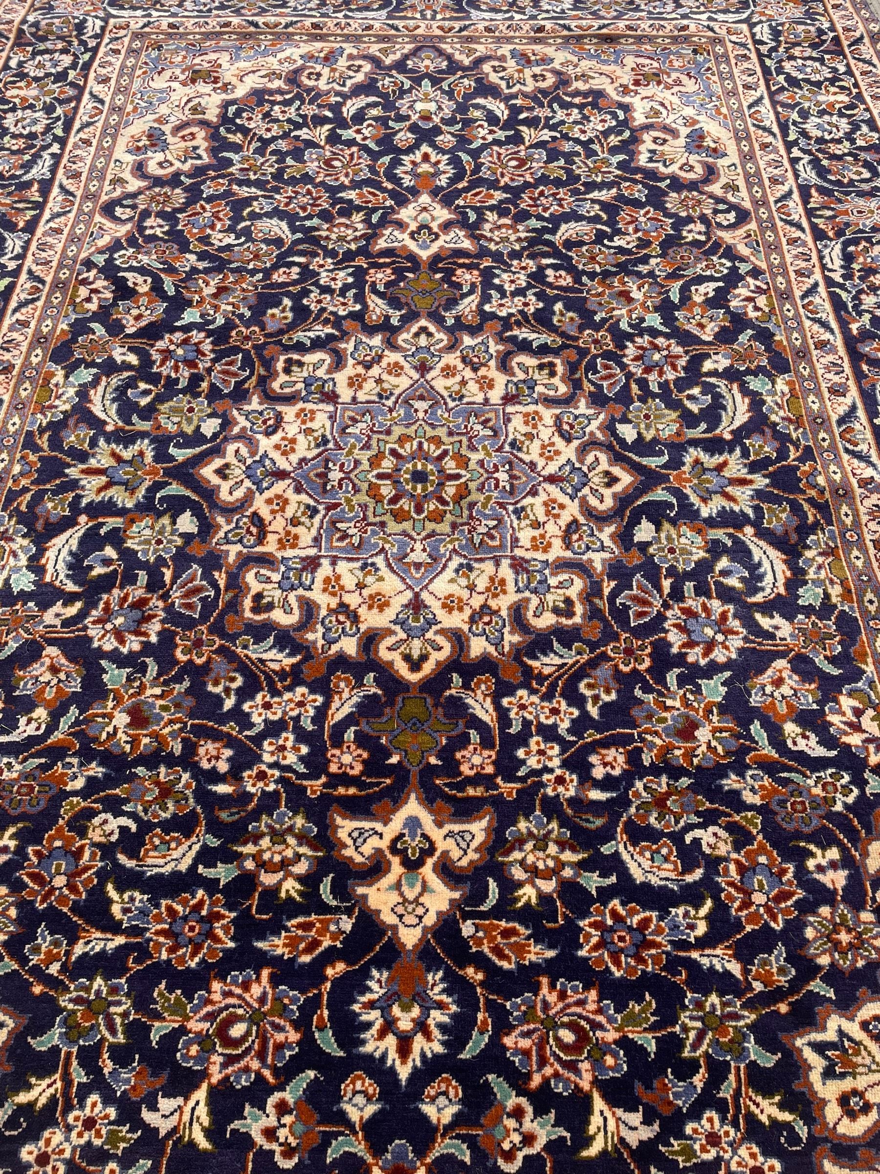 Persian Nain indigo ground, arabesque design, central start medallion surrounded by interlacing branches and palmettes, scrolling border with repeating stylised plant motifs, within guard stripes