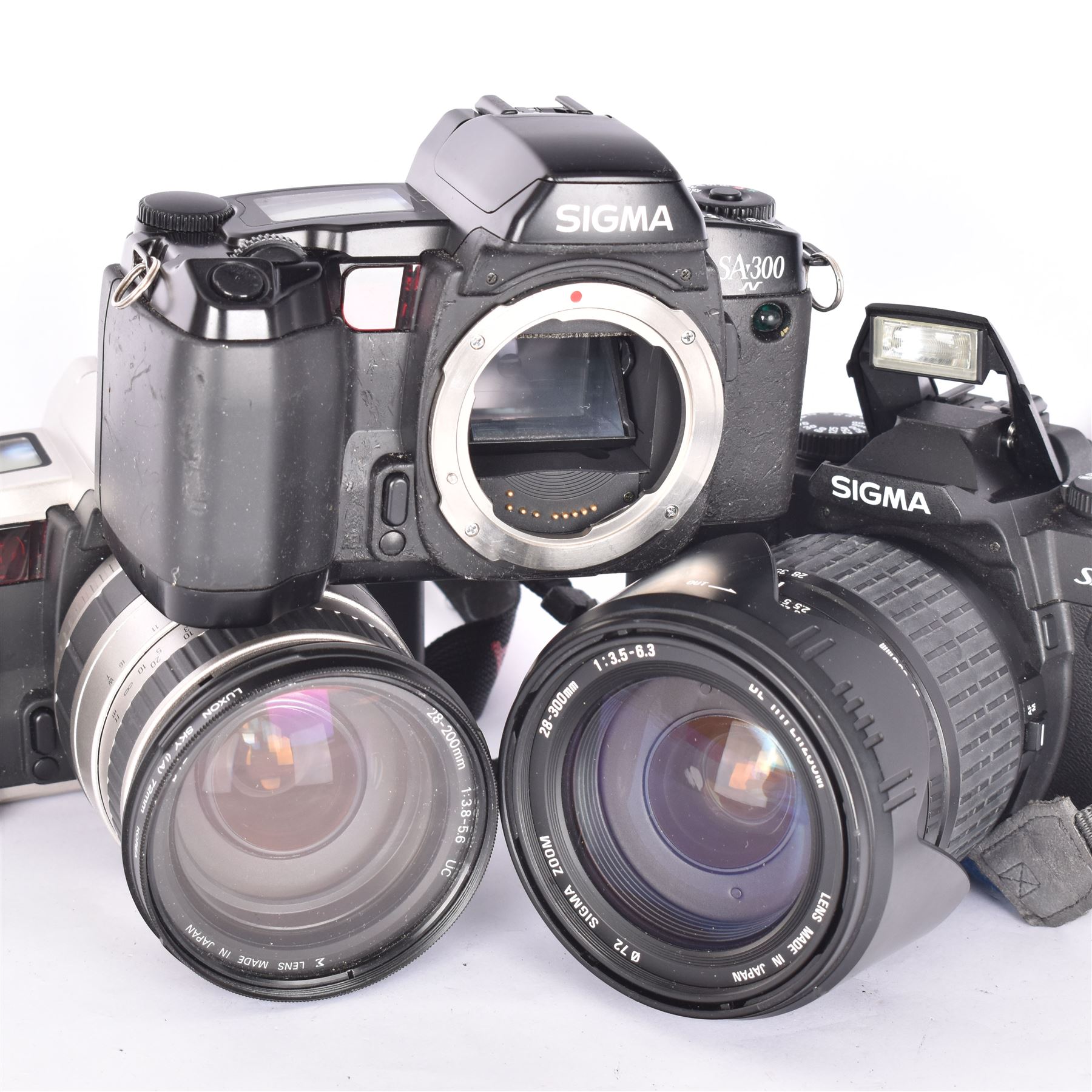 Three Sigma SLR camera bodies, to include SA-300 serial no. 8042778, SA-5 serial no. 1001611, with a Sigma 28-200mm 1:3.8-5.6 UC zoom lens, serial no. 2045647, and a Sa-7 serial no. 1002865, with a 28-300mm 1:3.5-6.3 DL Hyperzoom lens, serial no. 1003061