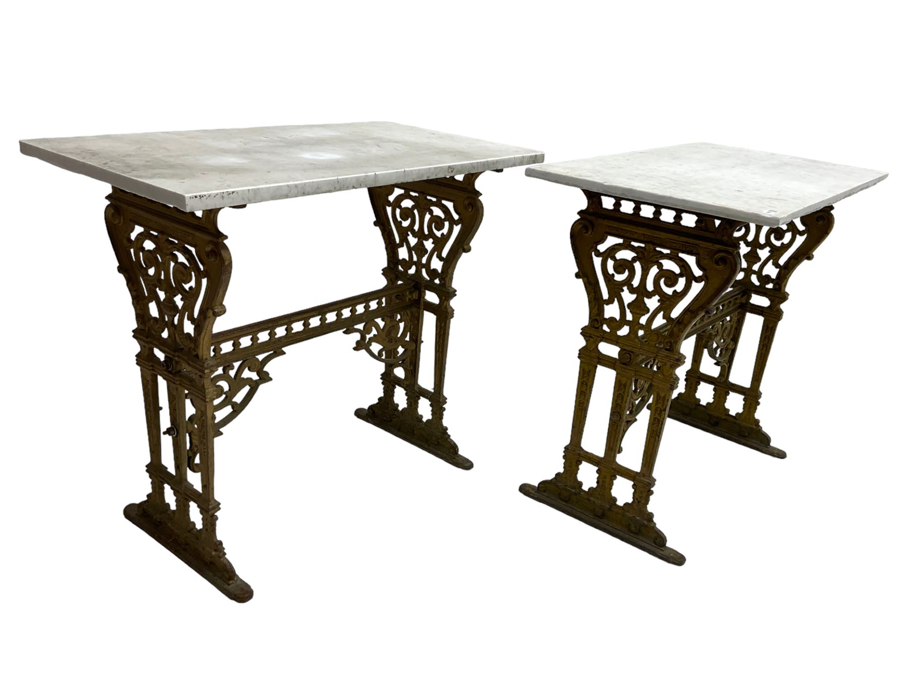 Pair of 19th century cast iron entrance tables, rectangular marble top over ornate gilt bases with scrolling foliate design and sledge feet, united by balustrade stretcher with scroll spandrels