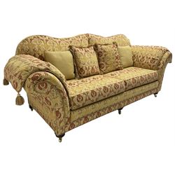 Steed Upholstery Ltd. - 'Lincoln' three-seat sofa upholstered in gold 'Olympia' floral pattern corded and tasselled fabric, together with scatter cushions and arm covers, on turned feet with brass castors