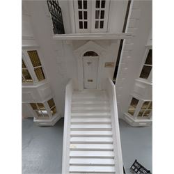 Large three storey modern dolls house, painted white with latticed windows, grey roof and metal fencing, with decorated interior, together with two dolls house garden rooms and two conservatories