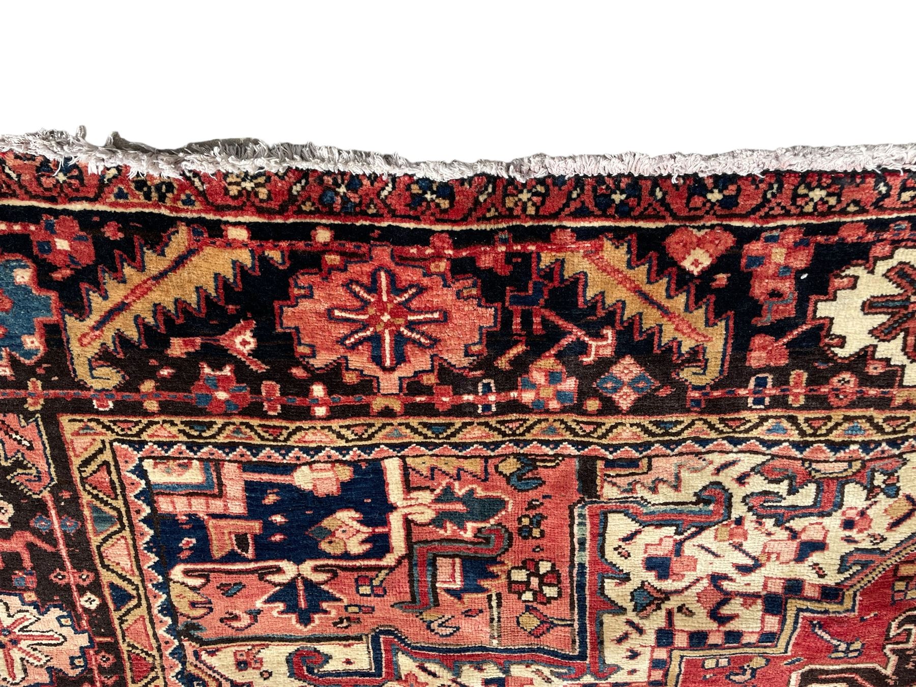 Persian Heriz red ground carpet, large central eight point medallion with projecting palmettes surrounded by small geometric motifs, decorated profusely with hooks, rosettes and animals, the busy border decorated with stylised foliate motifs within guard stripes 