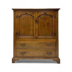 Oak drinks or media cabinet, projecting moulded cornice over two Gothic arch panelled doors on sliding tracks enclosing open storage, two drawers with brass drop handles, on bracket supports