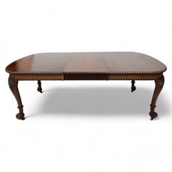 Early 20th century telescopic extending dining table, gardroon carved rectangular top with rounded ends, scrolled acanthus leaf carved cabriole supports with ball and claw feet, on brass castors, with two additional leaves  