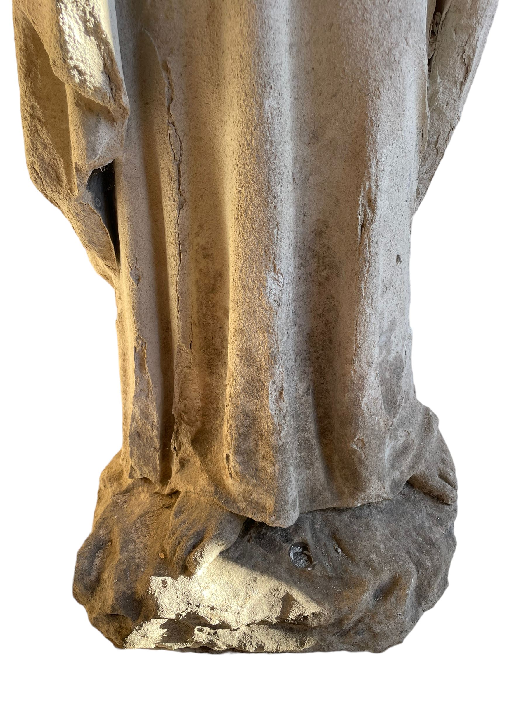 19th century weathered carved sandstone figure of Jesus Christ depicted as the Good Shepherd, draped in robes and holding a lamb, on a naturalistic base