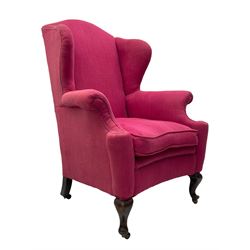 Georgian design hardwood-framed wingback armchair, arched cresting rail over curved wingback, rolled arms on scrolled cushioned supports, reverse bow-front, upholstered in claret red fabric with loose seat cushion, on cabriole front feet and brass castors 